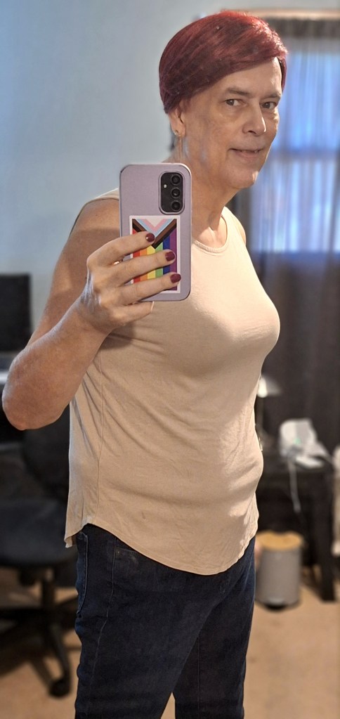Mirror selfie of Janet in a beige tank top and dark jeans